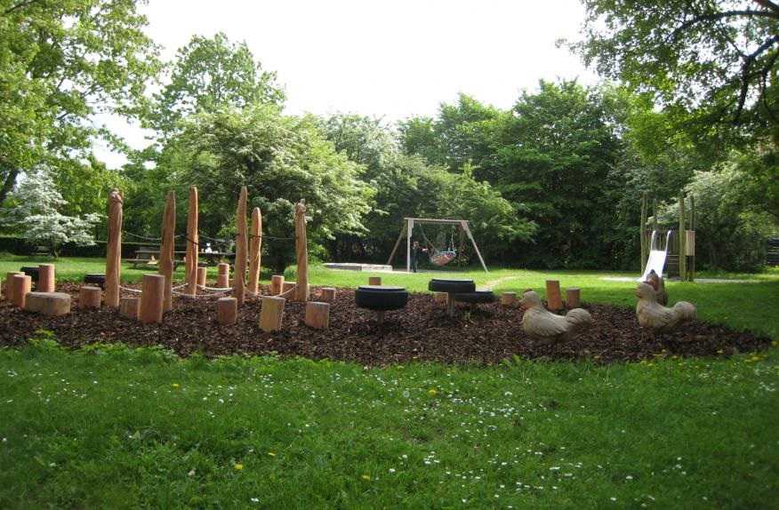 Tree stubs to climb on, swings and a slide at the playground at Pipers Park